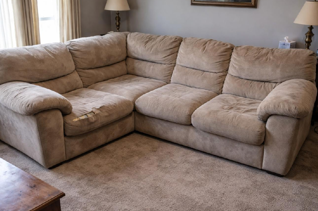 Large torn tan sectional sofa in a living room before professional removal in Owensboro KY